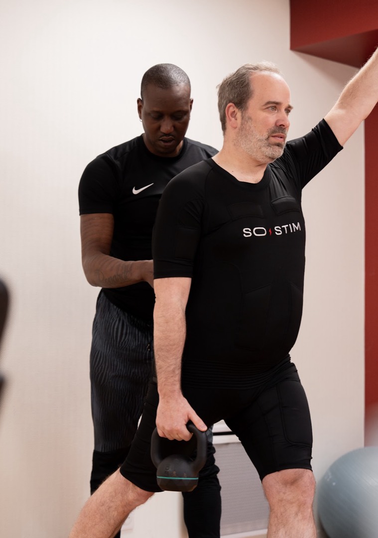 Coach SO STIM accompagnant un client lors d'une séance d'électrostimulation personnalisée