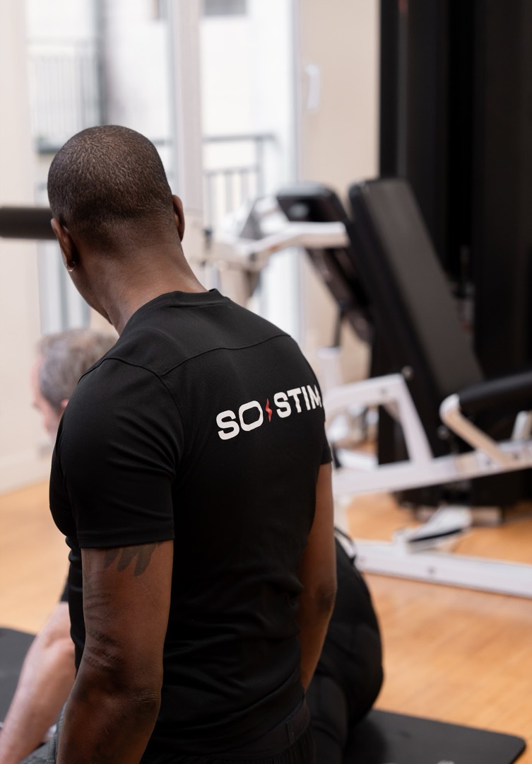Coach SO STIM dans un studio équipé de machines de musculation, comparaison EMS et musculation